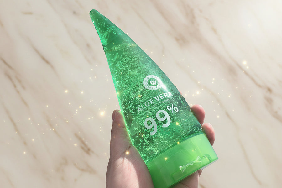 Green aloe vera gel bottle held against a blue sky