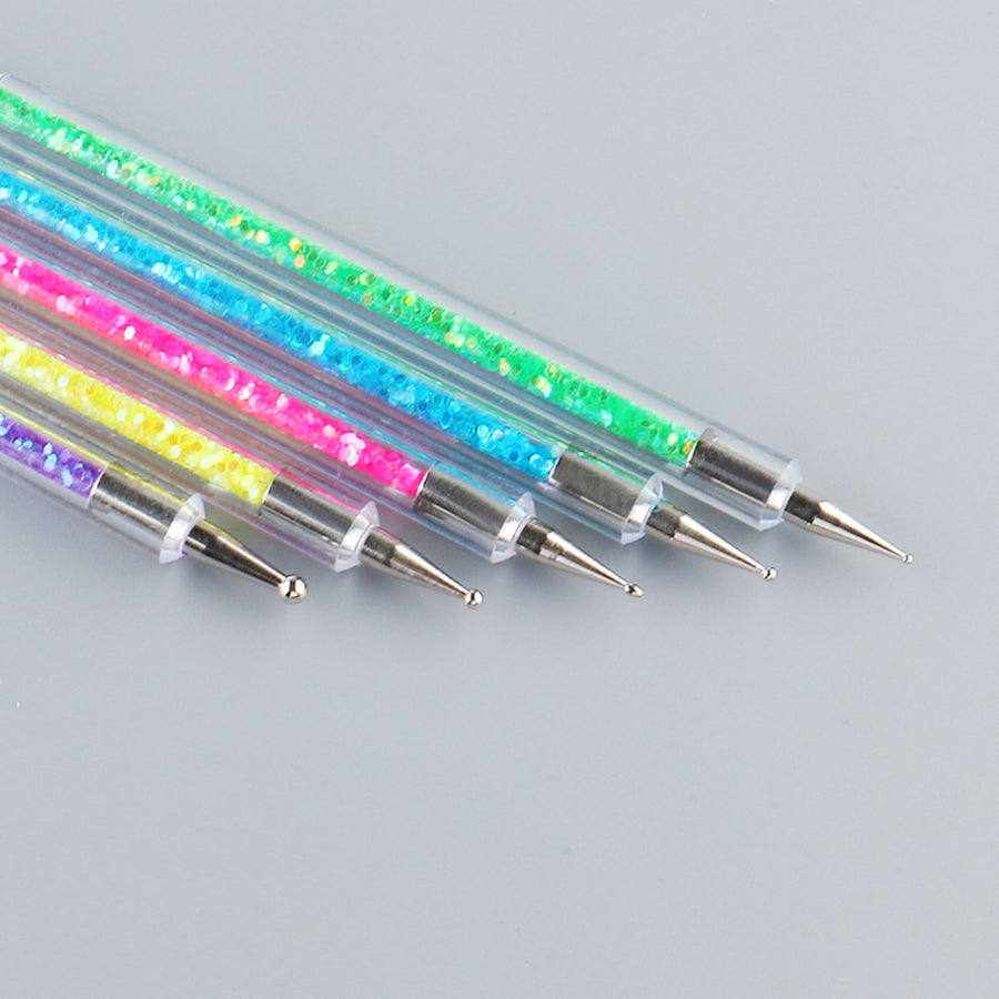 Set of colorful nail art tools with glittery handles on a gray background